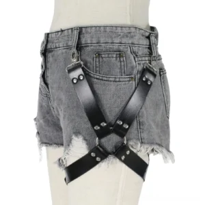 PU leather thigh harness with riveted cross straps and metal studs styled with grey frayed shorts, front angle shot