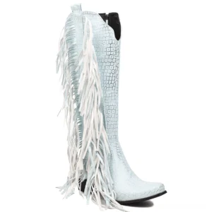 Light blue crocodile-textured knee-high gothic boots with long tassel fringe detail, side profile showing pointed toe silhouette