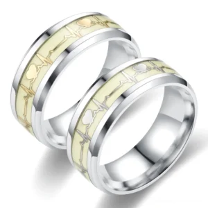 Luminous ECG heartbeat gothic ring pair, silver stainless steel with cream glowing heart pattern and gold metallic accents on white background