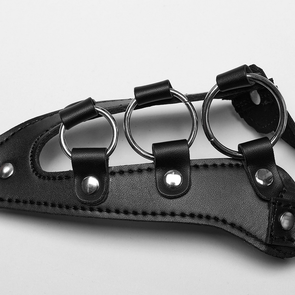Close-up top-down view of metal circular rings with rivet-fixed black leather straps from women's body harness