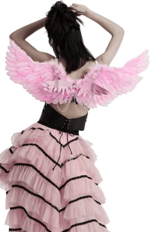 Back view of pink feathered wing harness worn with black corset and pink ruffle skirt gothic outfit