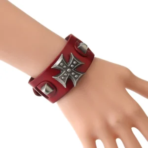 Red leather gothic cross wrap bracelet worn on wrist, showing adjustable toggle clasp and cone stud details