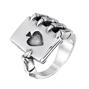 Skeleton claw holding spade card ring in polished silver-toned stainless steel, oblique overhead view on white background