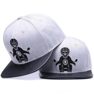 Skeleton motorcyclist gothic snapback cap front oblique view showing grey fabric and black leather brim with embroidered skull rider design