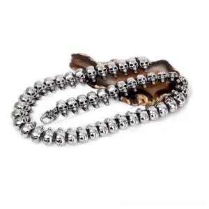 Gothic skull link necklace folded display, showcasing uniform silver skull beads and heavy-duty metal clasp on decorative agate coaster, top-down view