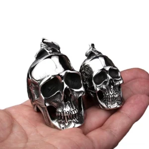 Dual skull pendant necklace comparison showing large and small stainless steel skulls in hand