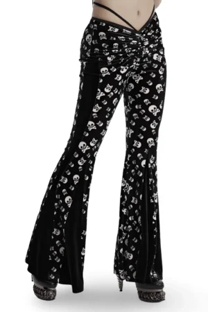 Skull print velvet flared gothic pants front side view on model showing ruched waist and cross strap detail