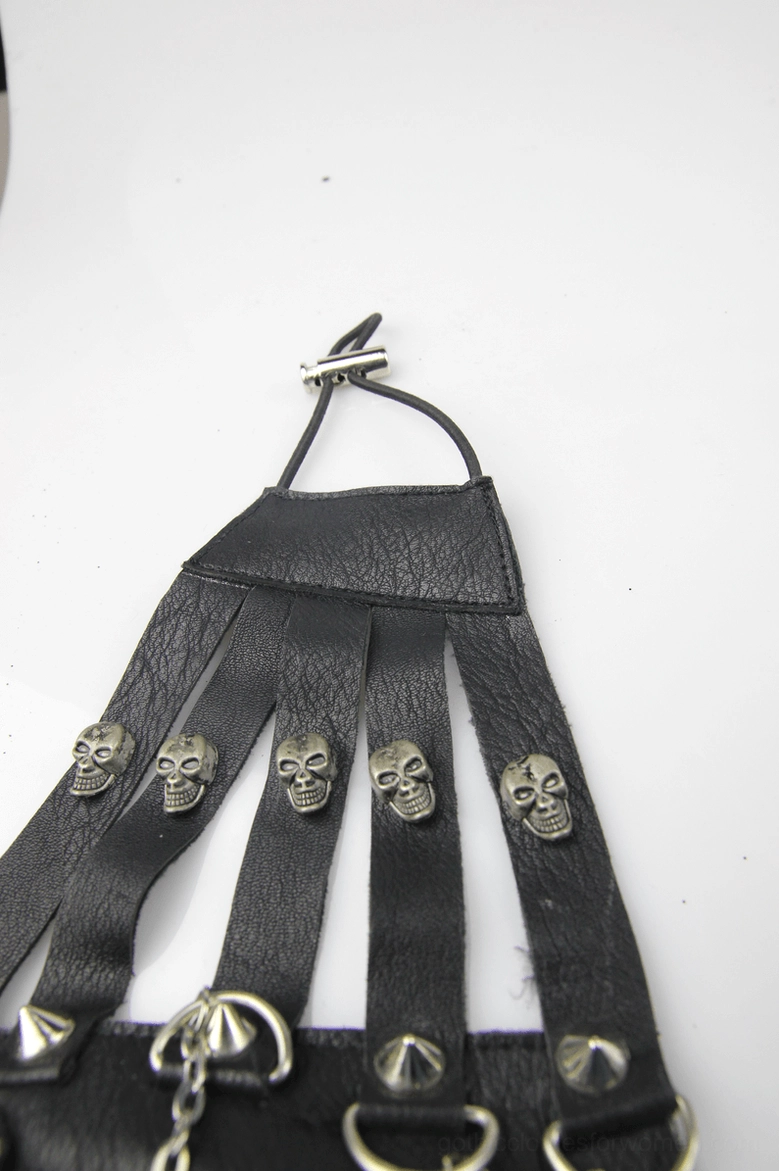Flat lay top-down view of black steampunk gothic mask showing skull studs, metal D-rings, adjustable neck strap and synthetic leather construction
