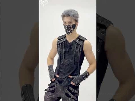 Full body front view of male model wearing black steampunk gothic face mask paired with studded leather gloves and punk rocker outfit