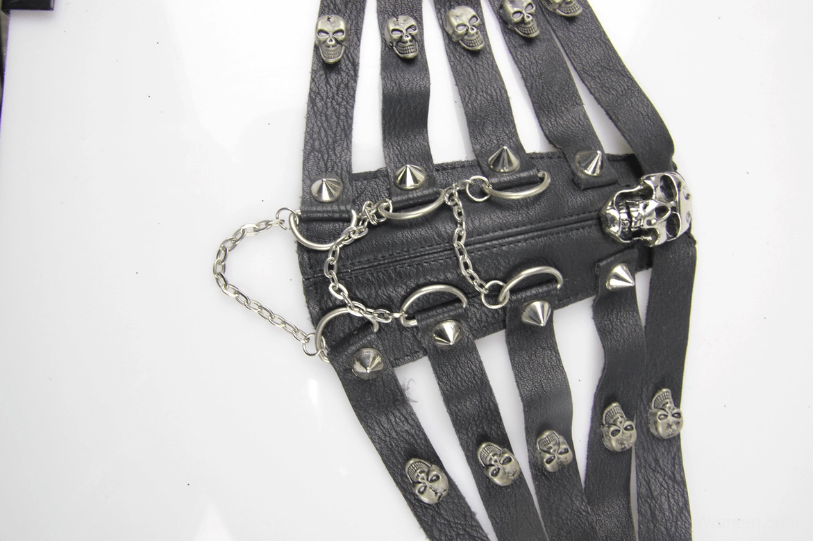 Close-up top-down flat lay of steampunk gothic mask hardware featuring metal chains, skull accents, spike studs and leather strap components
