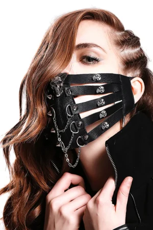 Black steampunk gothic face mask with skull studs and hanging metal chains, worn by female model in three-quarter side view