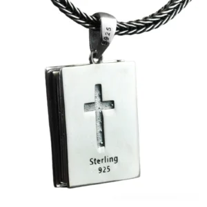 Religious book-shaped silver pendant front view showing detailed cross carving with 925 sterling mark