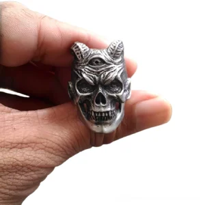 Three-eyed demon skull ring front view with textured aged silver finish and twin horns on white background