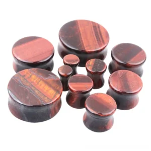 Multiple sizes of tigerite stone ear gauges arranged in flat display showing small to medium gauge options with deep wine-red striped stone texture, front view product photography