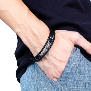 Men's treble clef leather bracelet worn on wrist side close-up view with casual dark clothing background