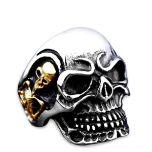 Triple skull gothic biker ring polished silver finish with gold accents, front-top angled view on white background