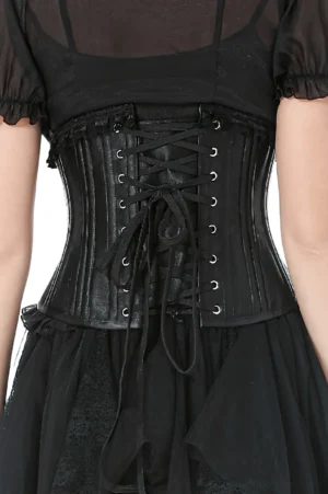 Close-up detail of black satin underbust corset front showing crisscross lace-up busk closure with metal eyelets and ruffled trim