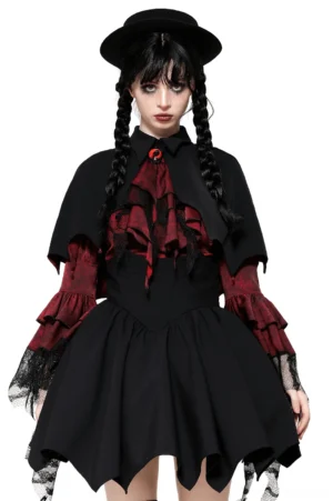 Gothic vampire cape with high collar and jeweled clasp worn by female model with twin braids and black top hat, front view showing bat-wing hem and red inner lining