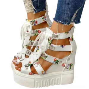 White floral platform wedge sandals with open toe and lace-up buckle closure, displayed on model in studio setting
