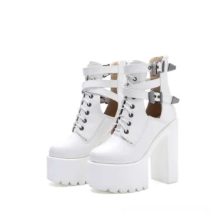 White platform lace-up ankle boots with decorative buckle straps and architectural cutout details, front three-quarter angle showcasing the substantial platform sole