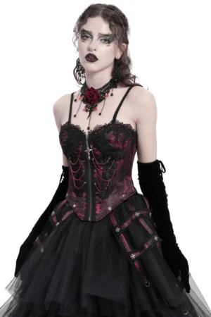 Wine red gothic corset with layered chains and cross pendant, front three-quarter view on goth model, showing brocade fabric and lace trim details