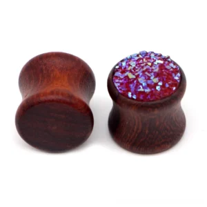 Close-up detail of wine red resin inlay on wooden ear gauge, showing iridescent sparkle and wood grain texture